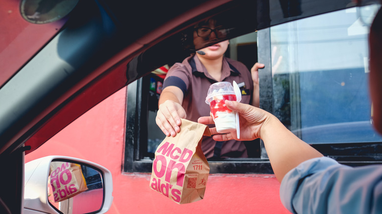 Worker handing meal to customer at McDonald's drive-thru
