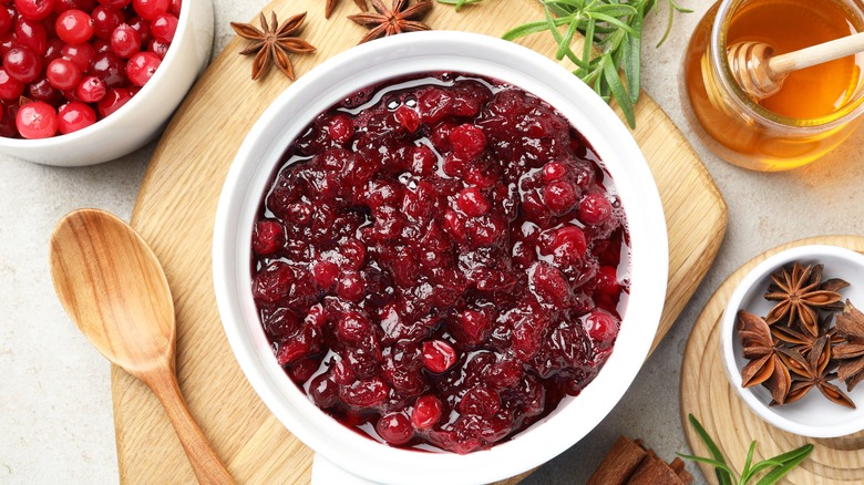 Cranberry sauce in white bowl on wooden board