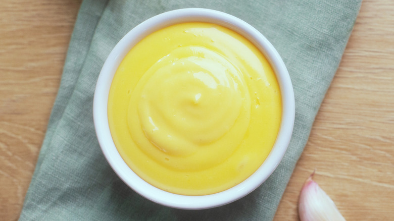 Bowl of aioli with garlic cloves alongside