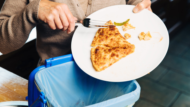Person pushing pizza into a trash can