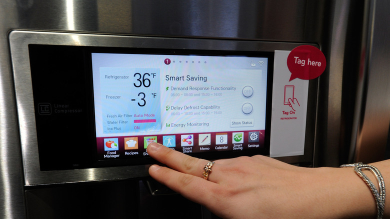 Person clicking buttons on a smart fridge
