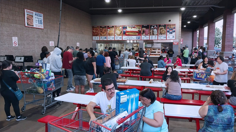 a group of people waiting to order at an outdoor Costco food court