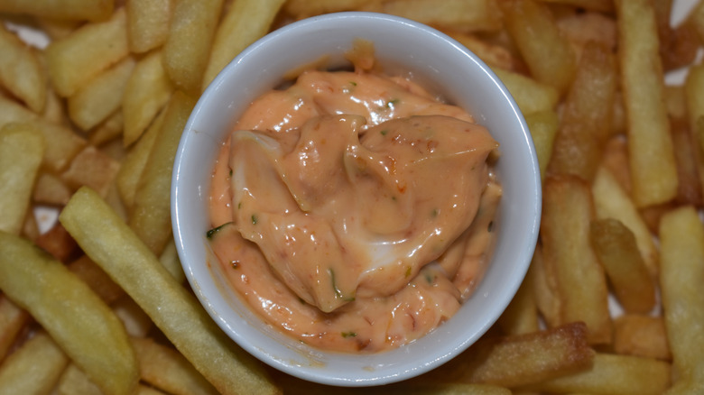 A bowl of special sauce sits on top of french fries.