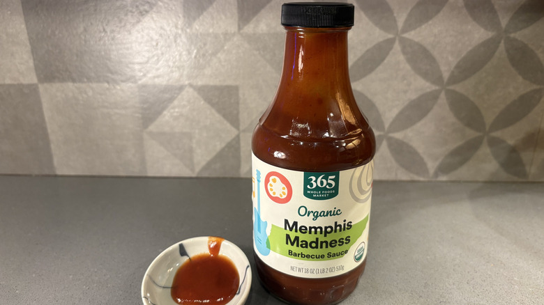 A bottle of 365 Organic Memphis Madness BBQ near a small cup of sauce