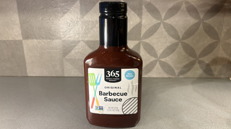 A bottle of 365 Original BBQ near a small cup of sauce