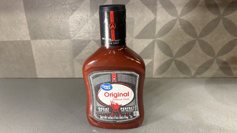 A bottle of Great Value Original BBQ near a small cup of sauce