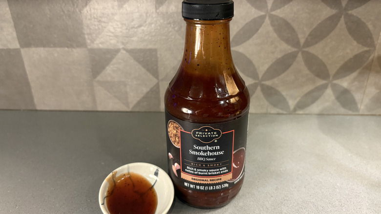 A bottle of Private Selection Southern Smokehouse BBQ near a small cup of sauce