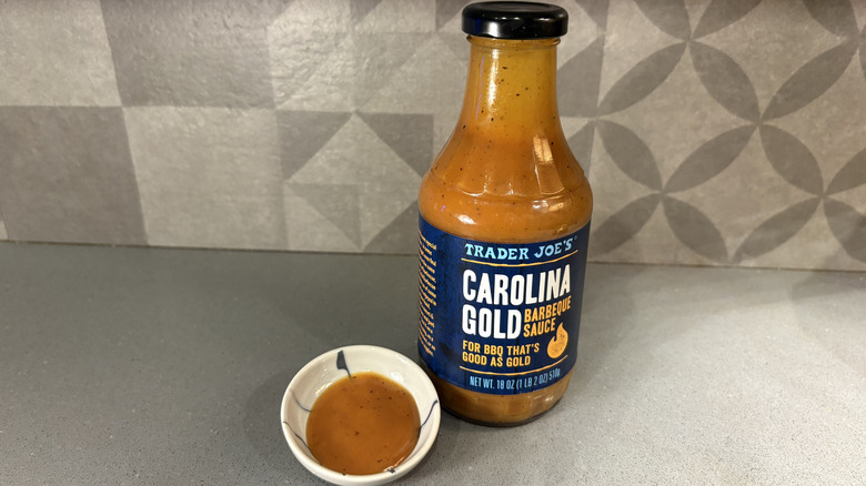 A bottle of Trader Joe's Carolina Gold BBQ near a small cup of sauce