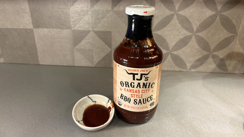A bottle of Trader Joe's Organic Kansas City Style BBQ near a small cup of sauce