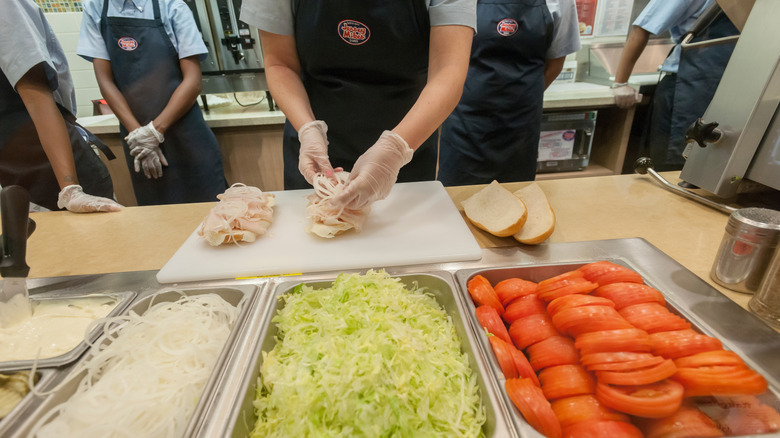 An employee tops a Jersey Mike's sub with ingredients