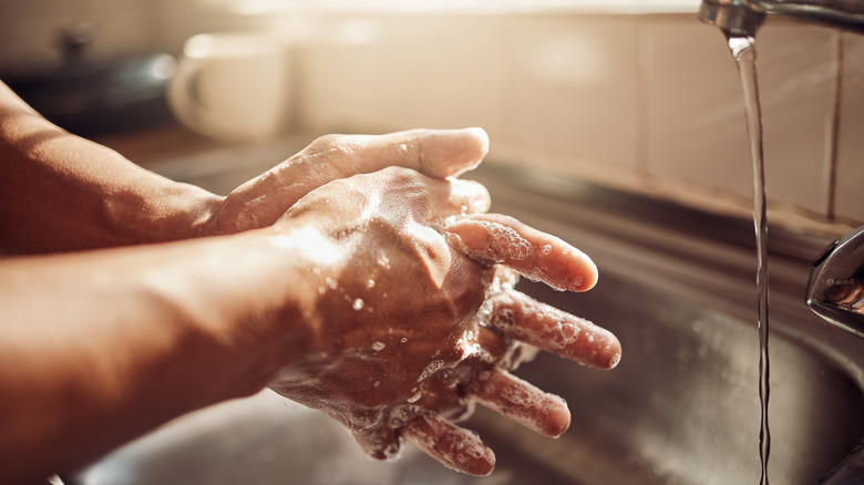A person washing their hands with soap and running water