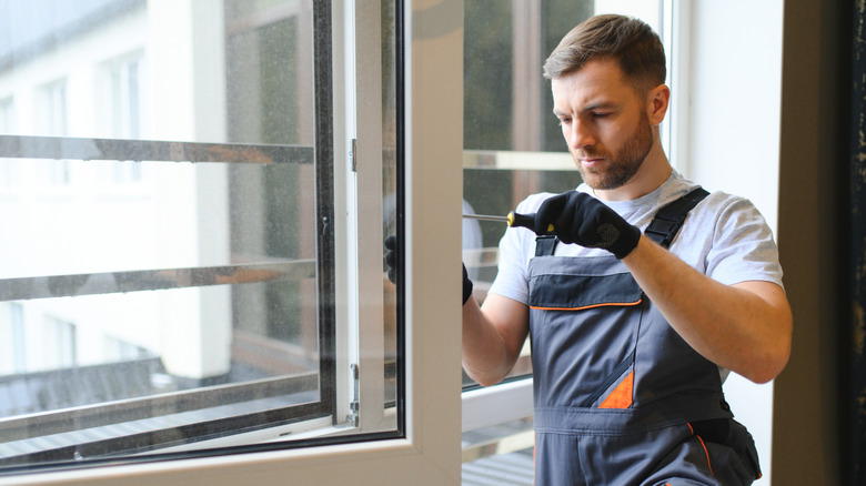 A man in overalls performing a home window installation