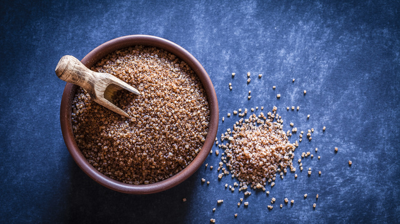 Bowl of brown sugar granules on a blue background