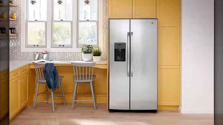 GE side by side refrigerator in a kitchen with blond wood cabinets
