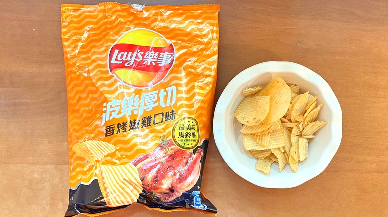 orange, wavy-patterned Juicy Chicken chip bag next to a white bowl of chips