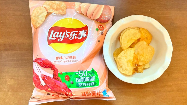 light pink Spicy Crayfish chip bag next to a white bowl of chips
