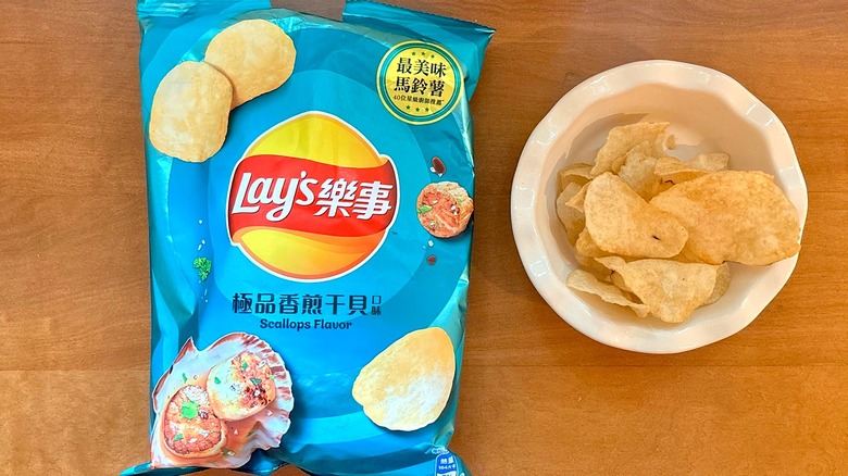 metallic blue Scallops chip bag next to a white bowl of chips