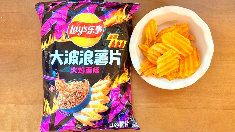 black and purple Spicy Turkey Ramen chip bag next to a white bowl of chips