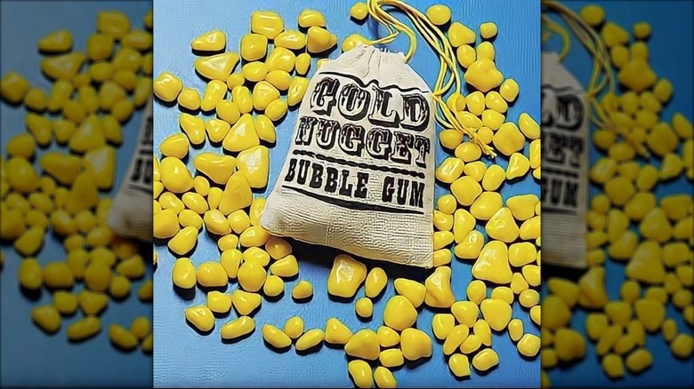 A bag of Gold Nugget Bubble Gum with some spilled out on a blue background