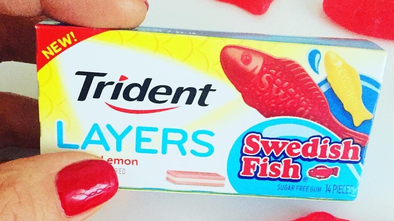 Woman holding a pack of Trident Layers Lemon Swedish Fish Gum