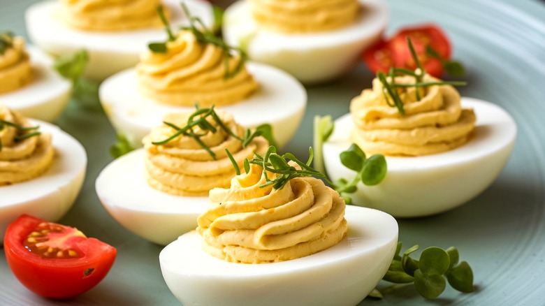 Close up of a plate of deviled eggs with fresh herbs on top