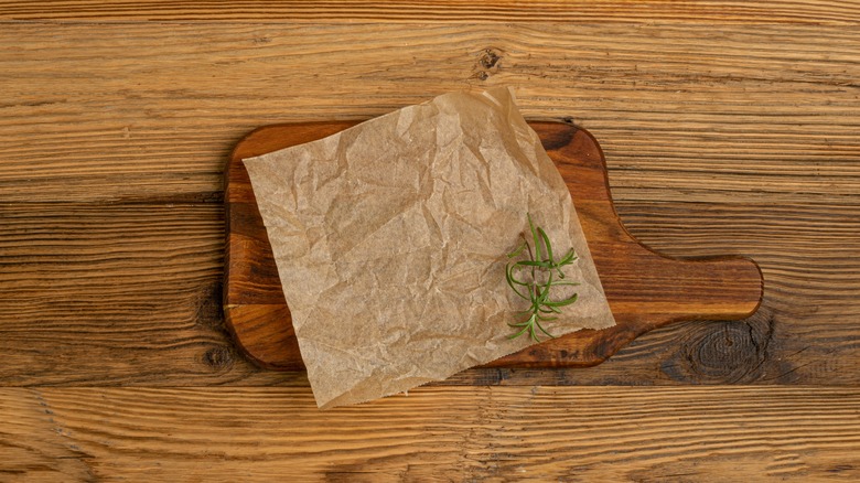 cutting board with brown parchment paper and herbs