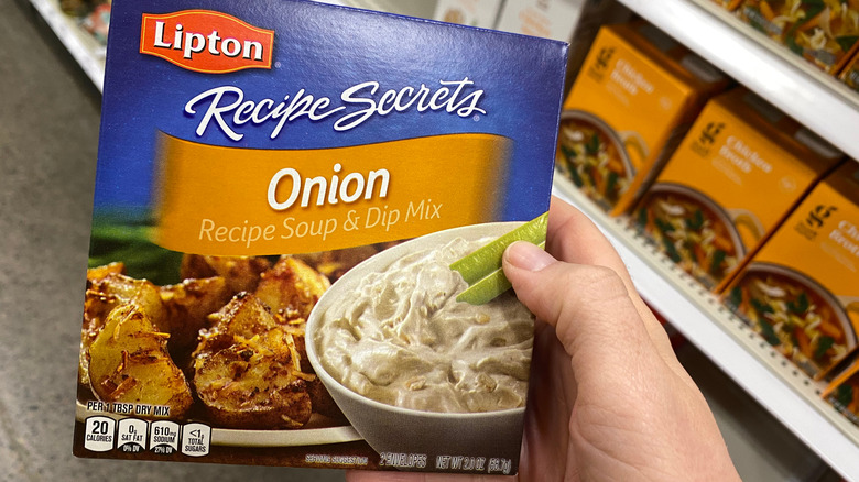 Hand holding box of Lipton Onion soup mix