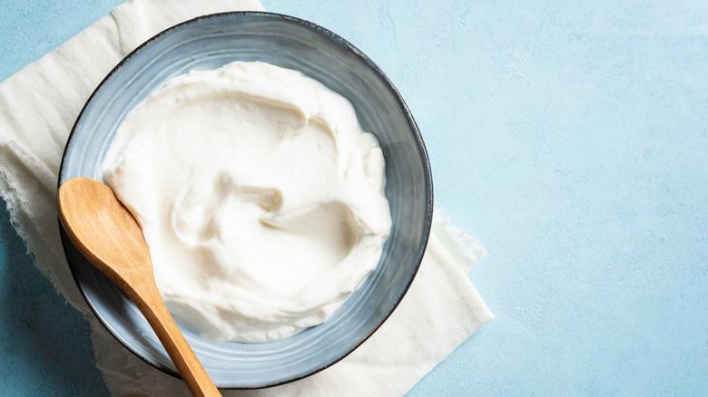 Sour cream in bowl with wooden spoon