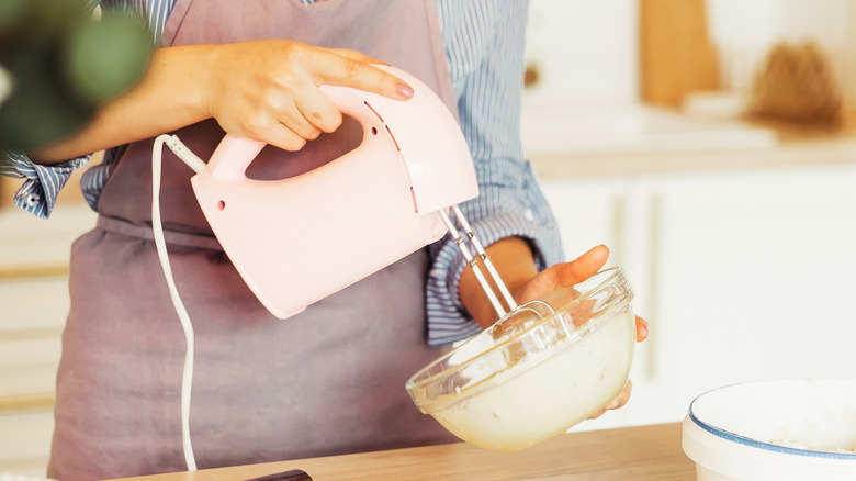 Woman using electric hand mixer