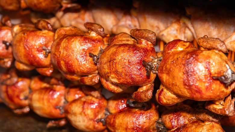 rotisserie chickens cooking on skewers