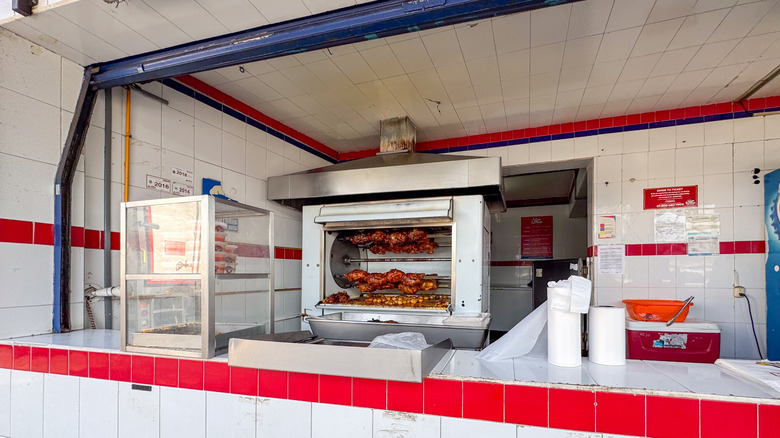 rotisserie chickens cooking behind a counter