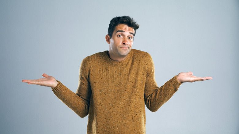 man shrugging on blue-gray background