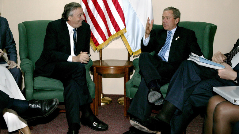 Argentina president Nestor Kirchner and George W. Bush sit side by side in green armchairs chatting