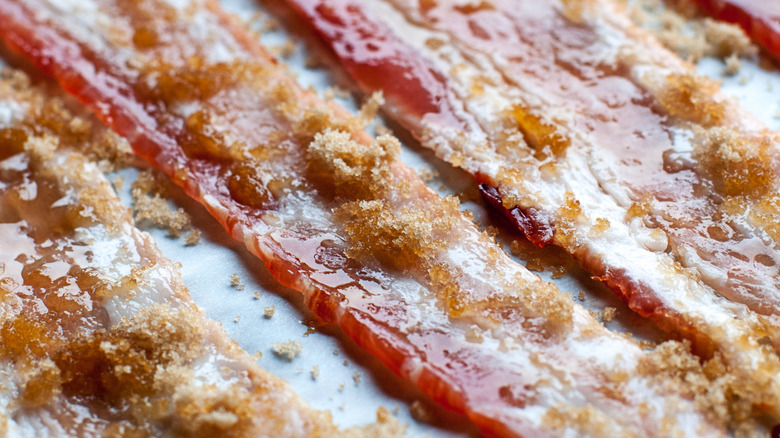 Rows of raw bacon sprinkled with brown sugar.