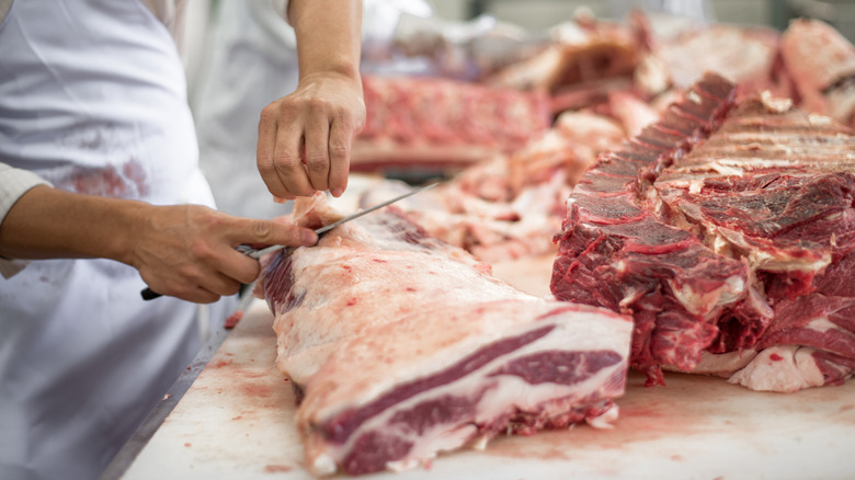 A butcher breaking down large primal cuts of beef