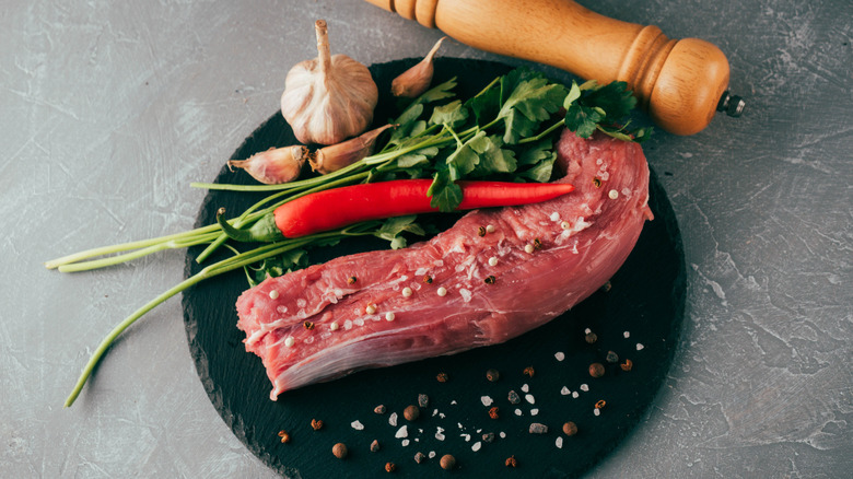 Pork tenderloin pieces in a pan with herbs