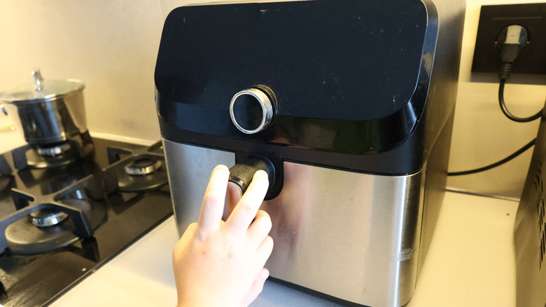 Person using an air fryer in a kitchen