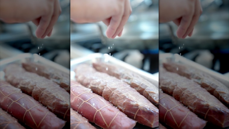 Person salting a pork tenderloin