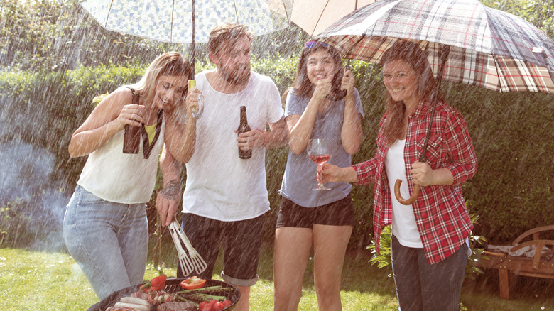 Group of people barbecuing in the rain and laughing despite the weather