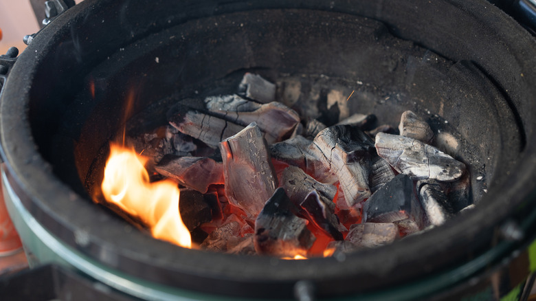 Charcoal briquettes on fire in the bowl of an outdoor grill