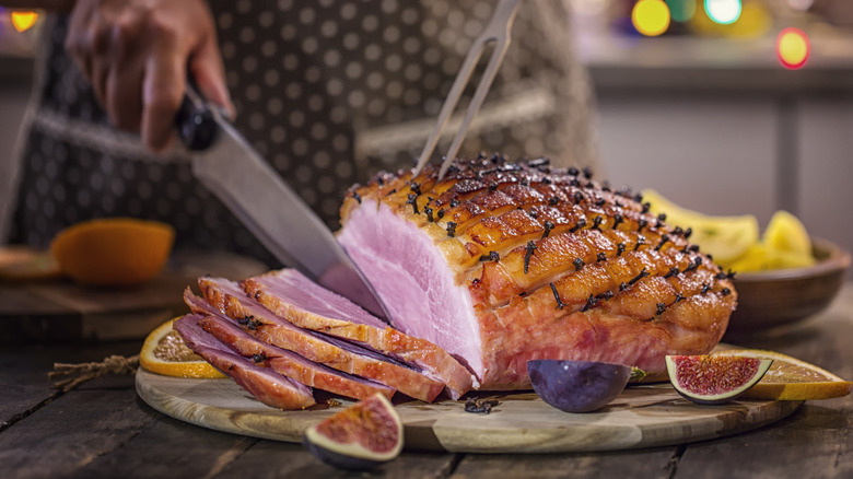 Slicing cooked ham on baord