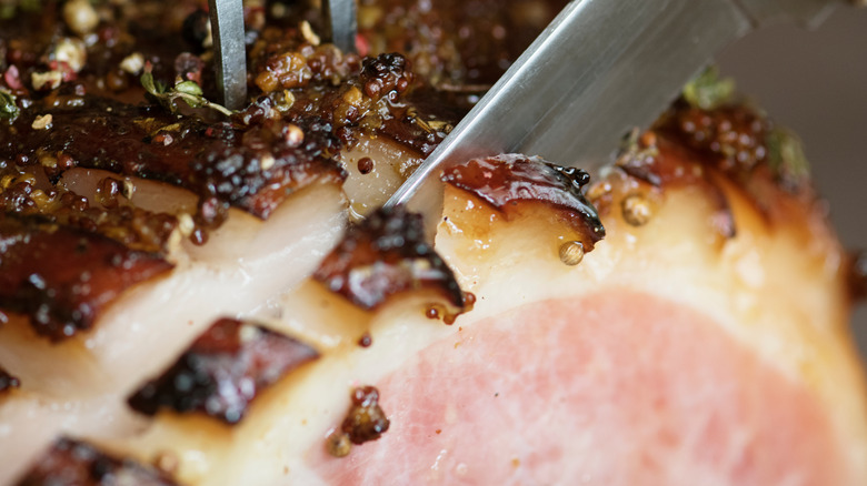 Knife slicing scored ham