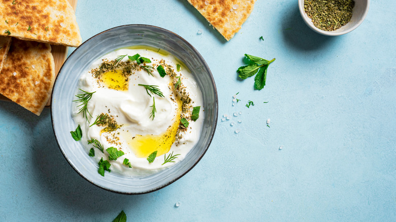 A bowl of labneh sits next to pita bread.