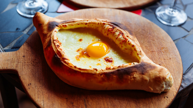 Georgian cheese boat khachapuri on a wooden serving tray