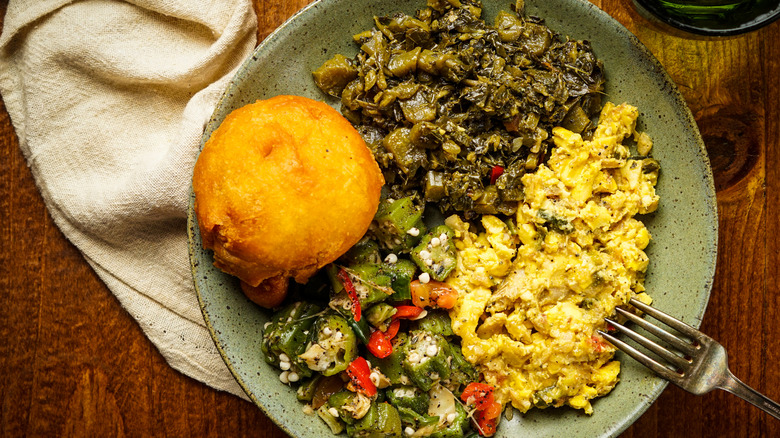 Plate of traditional Jamaican breakfast with ackee and saltfish, fried dumpling, okra, and callaloo