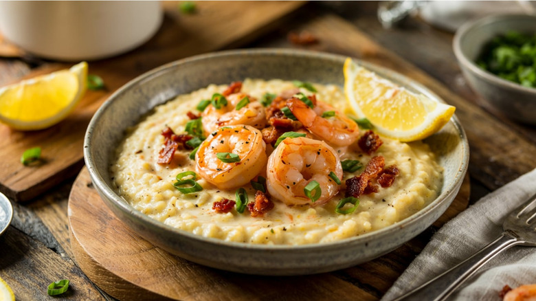 Plate of shrimp and grits with scallion and a wedge of lime
