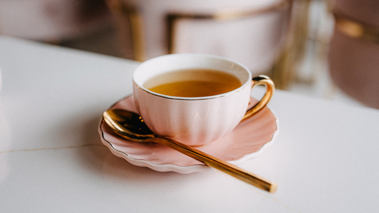 pink china teacup with golden spoon