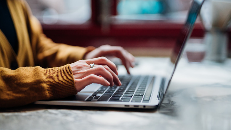 person's hands typing on laptop keyboard