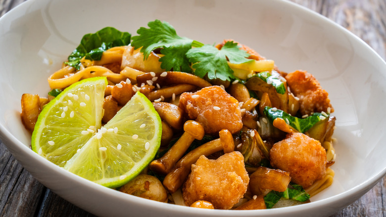 Stir-fry dish with chicken nuggets and limes