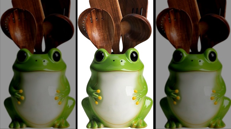 Ceramic frog with empty top filled with dark brown wooden kitchen utensils